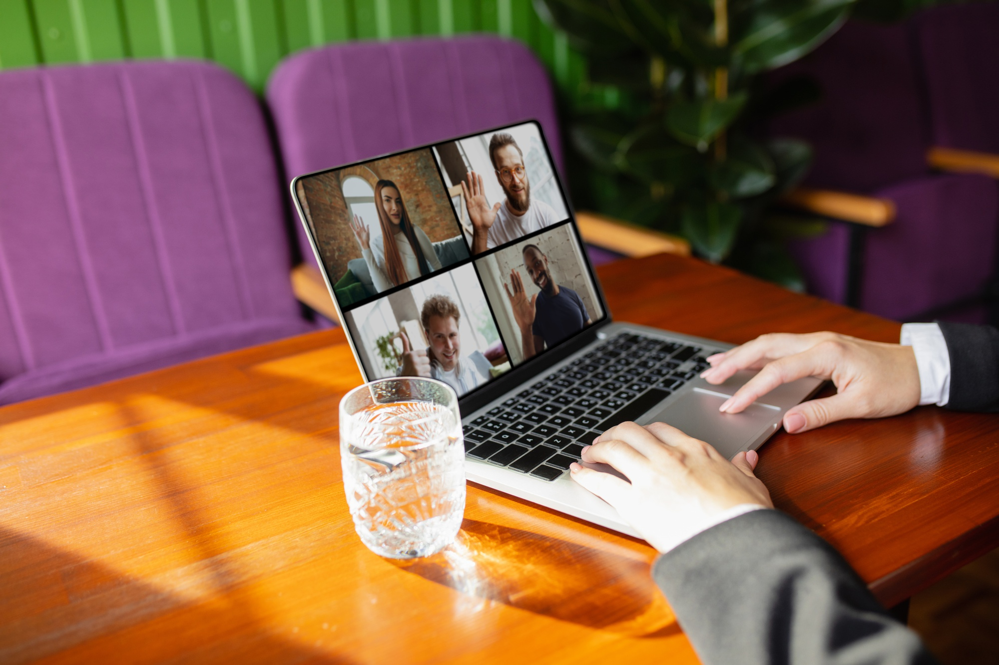 Homem bebendo água enquanto participa de uma reunião virtual do seu trabalho remoto no laptop.